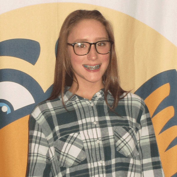 Young girl smiling with braces wearing glasses and a plaid shirt