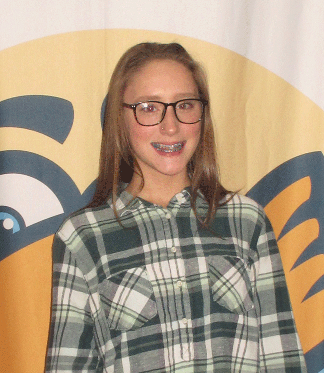Young girl smiling with braces wearing glasses and a plaid shirt